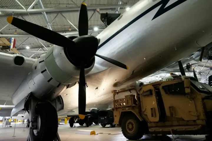 Avion à hélices et véhicule militaire stationnés dans un hangar aéronautique